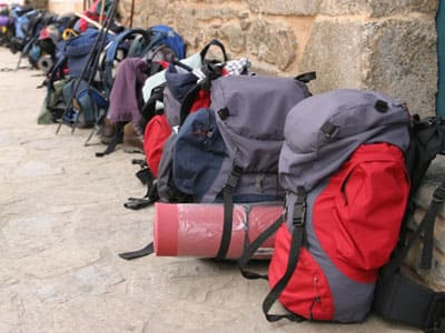 Backpacks lined against a wall waiting for bag transport